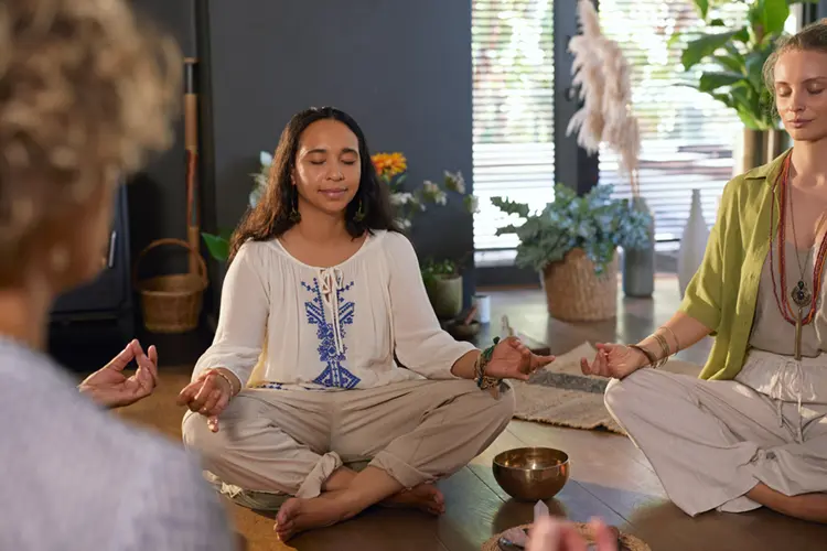 A person sitting cross-legged and meditating in a calm, naturally lit room